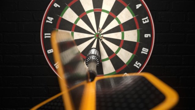 Darts arrow hitting in the bullseye of the dartboard hanging on the dark wall.