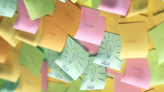 The collage of multiple colorful post-it notes on the wall with idea text.