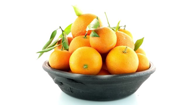 Tangerines on clay bowl isolated on white background