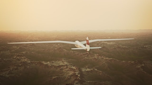 The white sailplane calmly gliding in the sky over the snow-covered mountains.