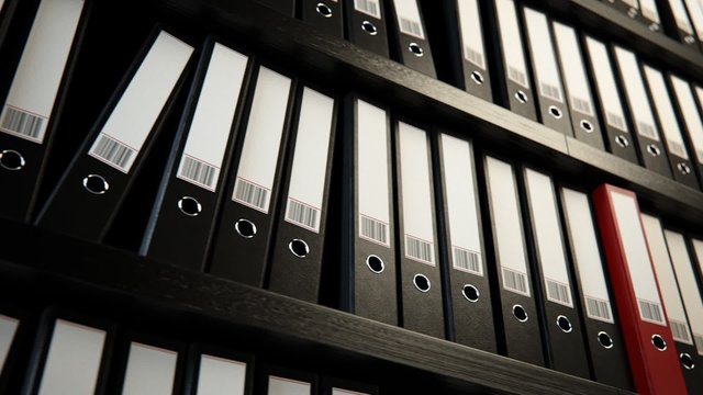 Close up on the row of the file black binders stacked on the wooden shelf.