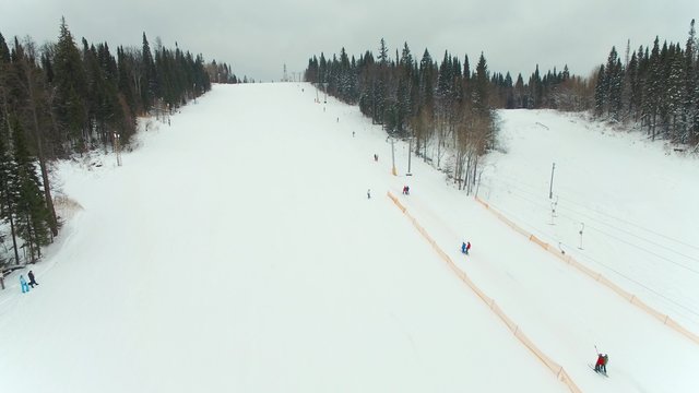 ski slope. snowboarders and skiers with rolling mountains. aerial video