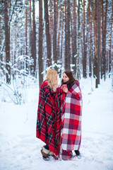 two girls sheltered red plaid hold mugs a drink in a snowy forest