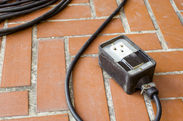 Old power outlet on brown floor tile, Outdoor view