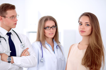 Fototapeta premium Confident doctor looking at patient while speaking to her, woman doctor in the background. Medical and health care concept