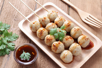 Grill pork balls pour with sweet spicy sauce on wooden table