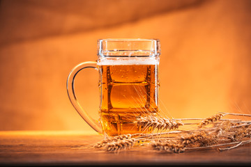 mug of light beer with ears of wheat on the wooden table