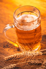mug of light beer with ears of wheat on the wooden table