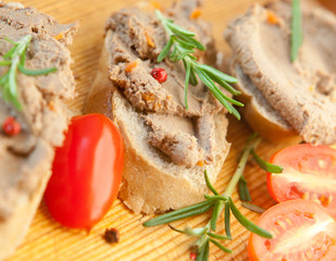 Chicken liver pate on bread with cherry tomatoes and a sprig of rosemary 