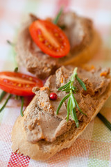 Chicken liver pate on bread with cherry tomatoes and a sprig of rosemary 
