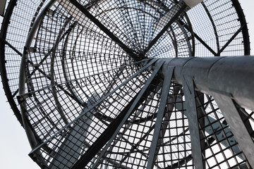 Metal spiral ladder, black silhouette over blue sky