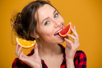 Portrait of beautiful smiling young woman eating citrus fruits