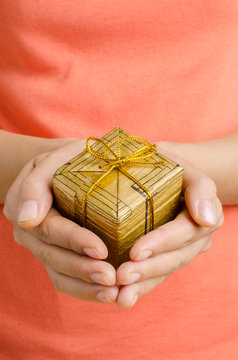 Woman holding golden gift box by hand