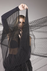Model hiding behind a black fabric