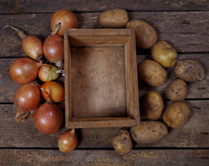 Potatoes and onion around wooden busket top view