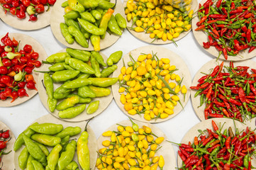 Colorful hot peppers in bright red, yellow, and green piles at farmers market display in Rio de Janeiro, Brazil