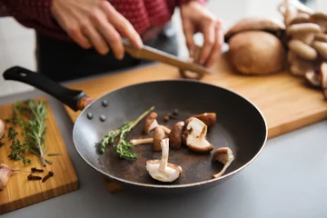 Photo sur Aluminium Cuisinier Closeup of mushrooms in a frying pan with woman slicing