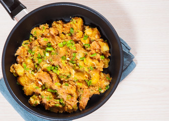 stewed meat with potatoes, onion in a frying pan