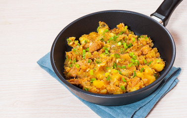 stewed meat with potatoes, onion in a frying pan