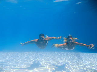 Young couple swimming underwater in the pool