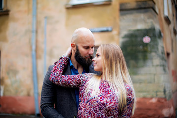 Adorable couple on a sunny day, standing near the wall embrace each other