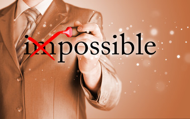 Businessman Hand turning the word Impossible into Possible with red marker