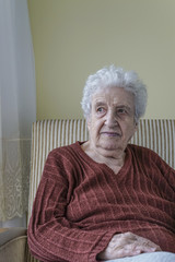 senior woman sitting in an armchair in home