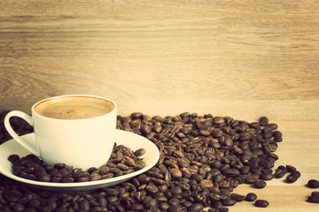 Coffee cup and coffee beans over wood