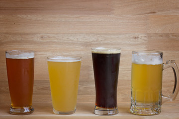 Four different glasses of beer over wood
