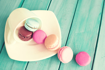 Colorful macaroons in a plate over turquoise wood