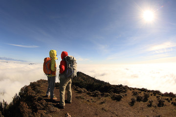 two successful  hikers enjoy the view on sunrise on mountain peak