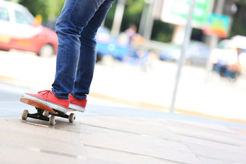 young skateboarder legs riding on skateboard on city