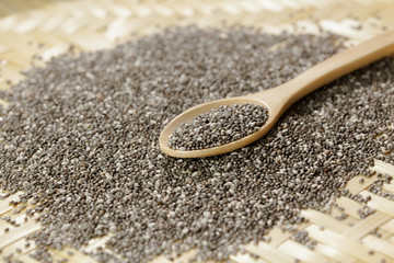 Handful of chia seeds on wood spoon and background