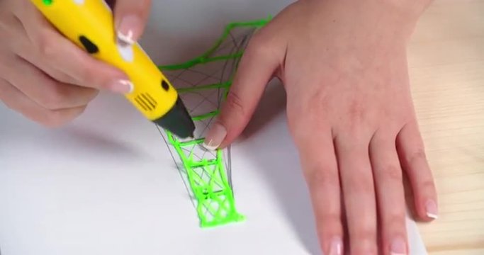 Hands of woman designer drawing Eiffel tower with 3d printing pen and correcting a mistake with wire cutter
