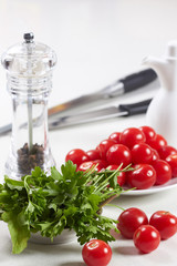 cherry tomatoes and parsley lie on a white table in the kitchen