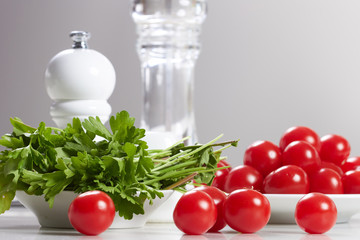 cherry tomatoes and parsley lie on a white table in the kitchen