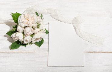 bunch of white roses on white table with empty card for you text
