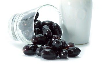 Black grapes in a glass isolated on a white background.