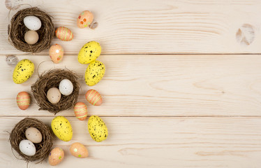 Fototapeta na wymiar Easter decoration - colorful eggs and nests on the wooden background.
