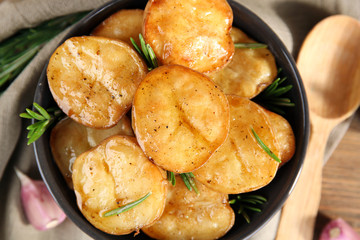 Delicious baked potato with rosemary in bowl on table close up