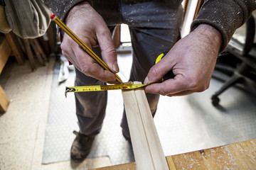 Carpenter measuring wood and marking with pencil