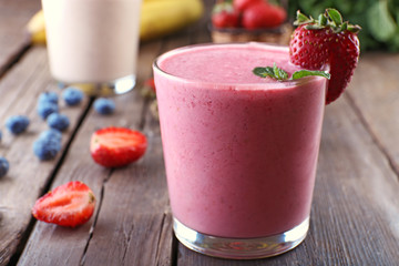Glasses of fresh cold smoothie with fruit and berries, on wooden background