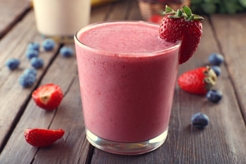 Glasses of fresh cold smoothie with fruit and berries, on wooden background