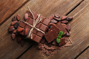 Chocolate pieces, shavings and cocoa beans on color wooden background