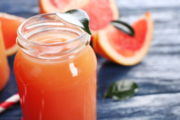 Grapefruit juice in bottles and fresh fruits on dark blue wooden background