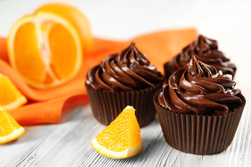 Chocolate cupcakes served with orange on table