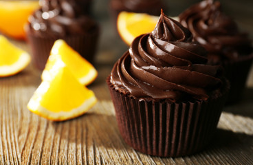 Chocolate cupcakes and cut orange on wooden table
