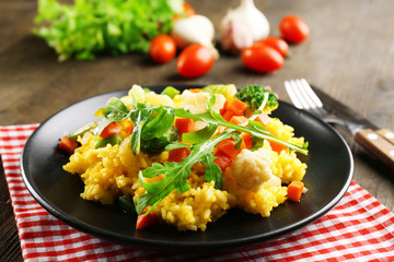 Black plate with vegetable risotto on served wooden table