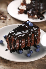 Chocolate cake with chocolate cream and fresh blueberries on plate, on wooden background