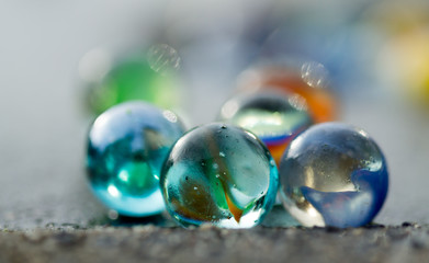 Marbles on the sidewalk close up.
Diversity of colors. Blurry in the back.